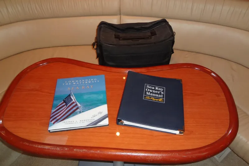 Shel 'b' Gale Yacht Photos Pics Sea Ray 380 Sundancer 2001 manuals on a wooden table with a black bag.