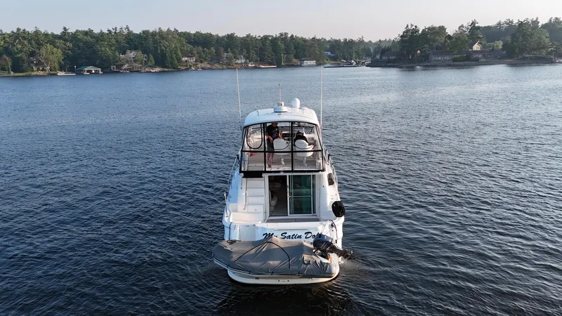 My Satin Doll Yacht Photos Pics 2001 Sea Ray 480 Sedan Bridge yacht on a serene lake with forested shoreline.
