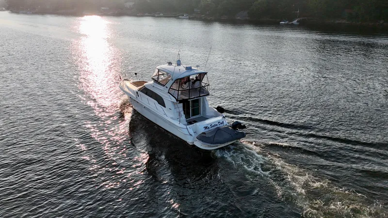 My Satin Doll Yacht Photos Pics 2001 Sea Ray 480 Sedan Bridge yacht cruising on a serene waterway at sunset.