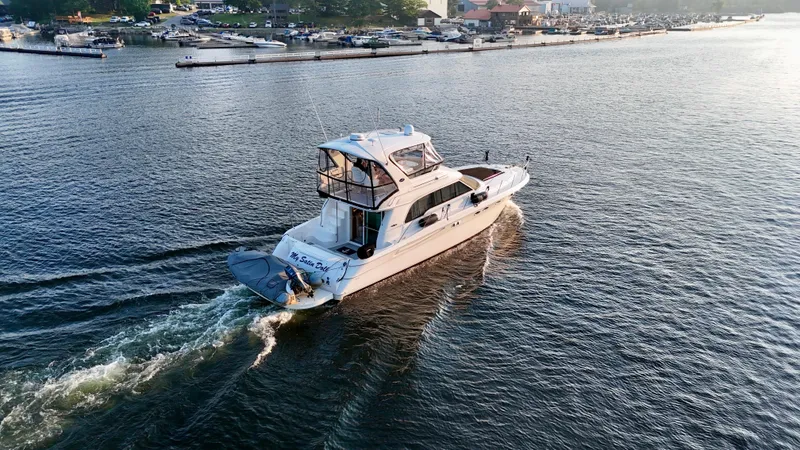 My Satin Doll Yacht Photos Pics 2001 Sea Ray 480 Sedan Bridge cruising on a calm lake near a marina.