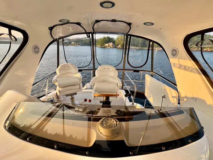 My Satin Doll Yacht Photos Pics 2001 Sea Ray 480 Sedan Bridge interior with helm and seating, overlooking serene water.