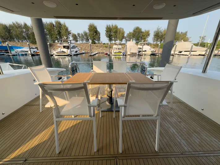  Yacht Photos Pics Outdoor dining area on 2022 Absolute 60 Fly yacht, featuring elegant chairs and wooden table.