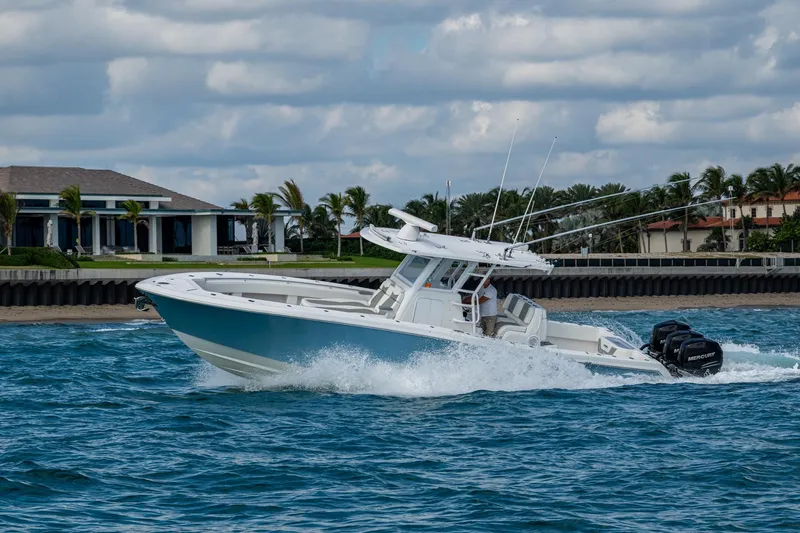  Yacht Photos Pics 2023 Invincible 36 Open Fisherman boat cruising on blue ocean near luxury waterfront homes.