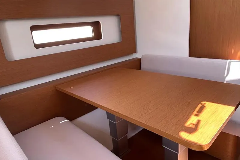  Yacht Photos Pics Interior of 2024 Beneteau First 44 yacht, featuring a wooden dining table and seating.