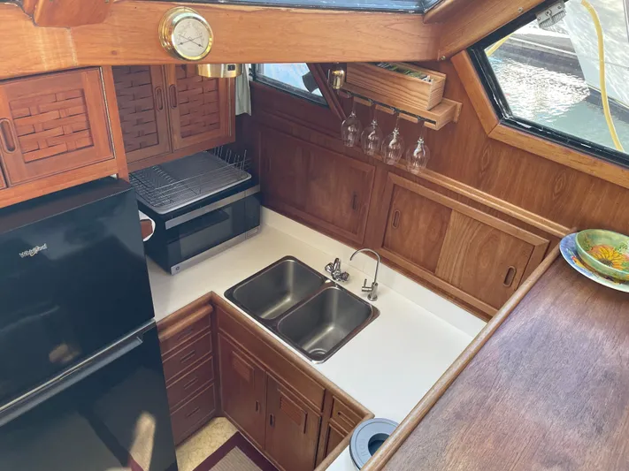 Safe N Sound Yacht Photos Pics 1988 Canoe Cove Tri Cabin kitchen with wood cabinetry, dual sink, and black refrigerator.