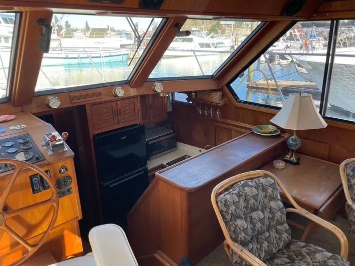 Safe N Sound Yacht Photos Pics 1988 Canoe Cove Tri Cabin interior with wood finish, steering wheel, and marina view.