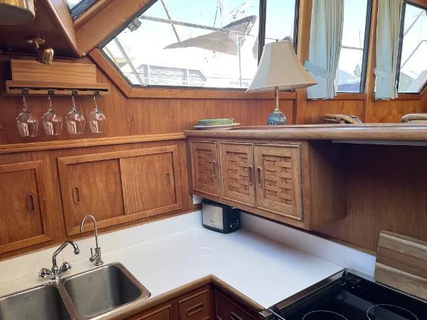 Safe N Sound Yacht Photos Pics 1988 Canoe Cove Tri Cabin kitchen with wood cabinets, sink, and glass rack.
