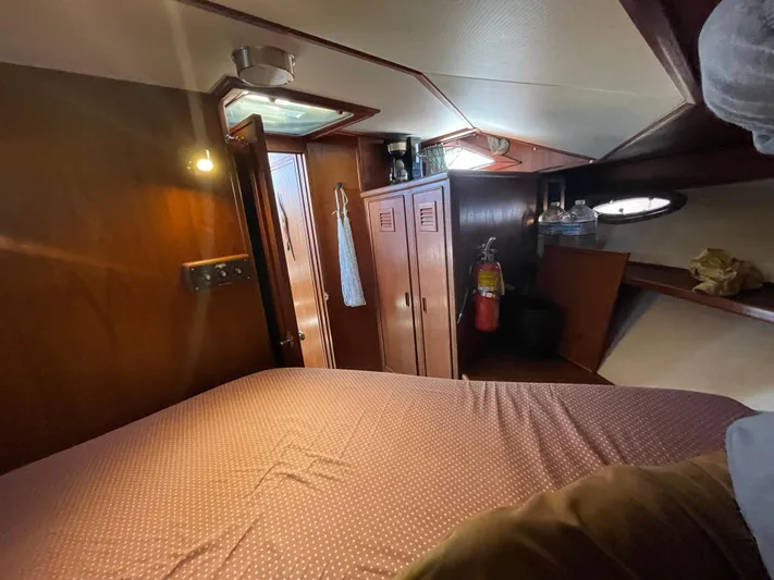 Safe N Sound Yacht Photos Pics 1988 Canoe Cove Tri Cabin interior with bed, wooden cabinets, and fire extinguisher.