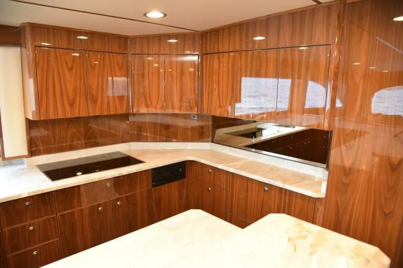 Another Day In Paradise Yacht Photos Pics Luxurious kitchen interior of 2017 Viking 80 Sky Bridge yacht with wood cabinetry and marble countertops.