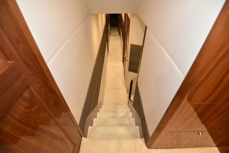 Another Day In Paradise Yacht Photos Pics Staircase inside 2017 Viking 80 Sky Bridge yacht with wooden paneling and carpeted steps.