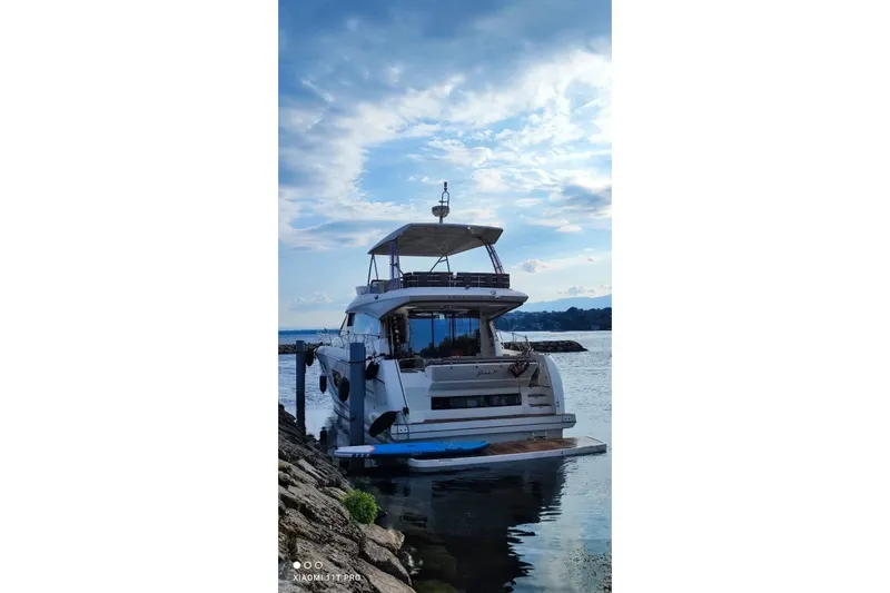 Yacht Photos Pics Luxury 2016 Prestige 550 yacht docked by rocky shore under blue sky.
