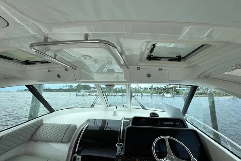 Nothing But Fine Yacht Photos Pics Interior view of 2022 Pursuit OS 385 Offshore boat, featuring helm and seating area.