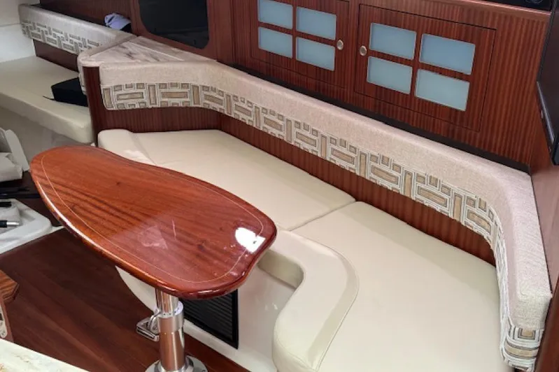 Nothing But Fine Yacht Photos Pics Interior of 2022 Pursuit OS 385 Offshore boat with elegant seating and wooden table.