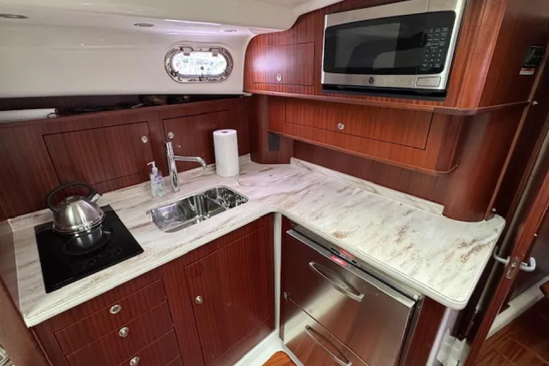 Nothing But Fine Yacht Photos Pics Luxurious 2022 Pursuit OS 385 Offshore yacht kitchen with modern appliances and elegant wood cabinetry.