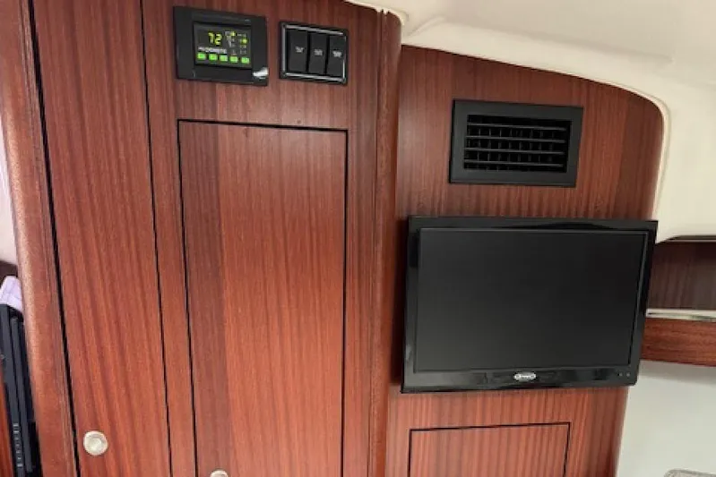 Nothing But Fine Yacht Photos Pics Interior of 2022 Pursuit OS 385 Offshore with wood paneling and mounted TV.
