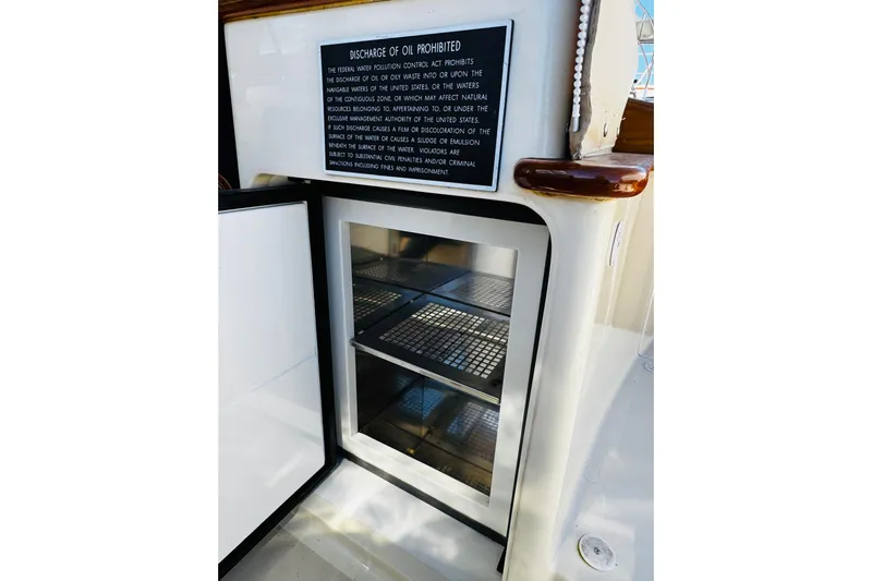 Maverick Yacht Photos Pics Open storage compartment on 2012 Hinckley Picnic Boat MKIII with oil discharge warning sign.