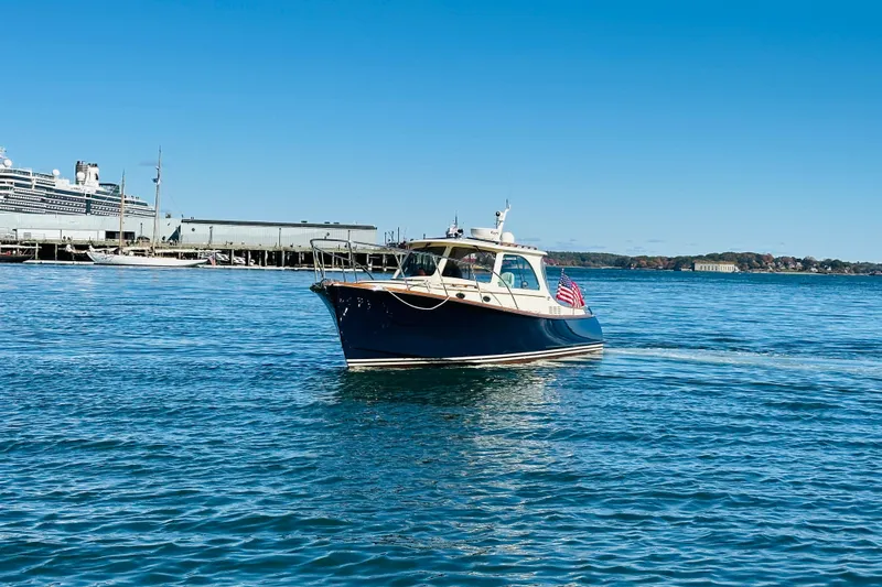 Maverick Yacht Photos Pics 2012 Hinckley Picnic Boat MKIII cruising in a harbor with a large ship in the background.