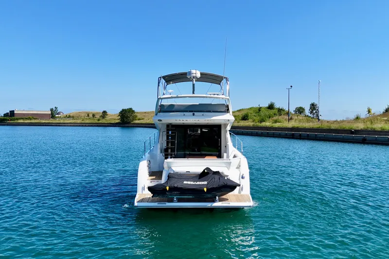  Yacht Photos Pics 2023 Prestige 460 yacht with jet ski on deck, docked in serene waters.