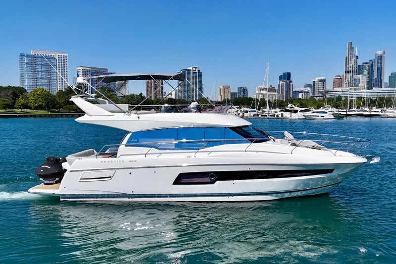  Yacht Photos Pics 2023 Prestige 460 yacht cruising in urban waterfront with city skyline backdrop.