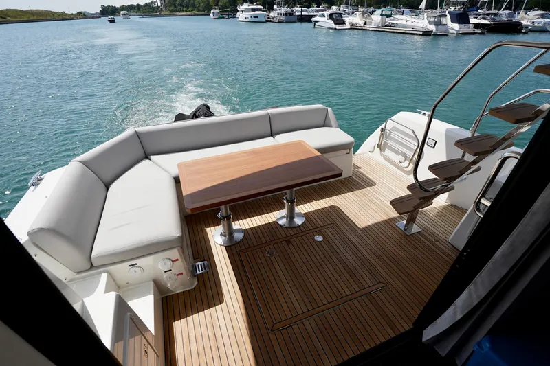  Yacht Photos Pics Luxurious 2023 Prestige 460 yacht deck with seating, table, and scenic water view.