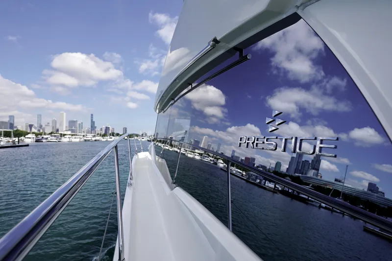  Yacht Photos Pics 2023 Prestige 460 yacht cruising near city skyline under blue sky.