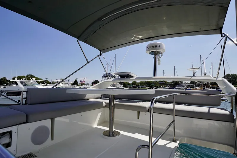  Yacht Photos Pics 2023 Prestige 460 yacht deck with seating, under a canopy, in a marina setting.