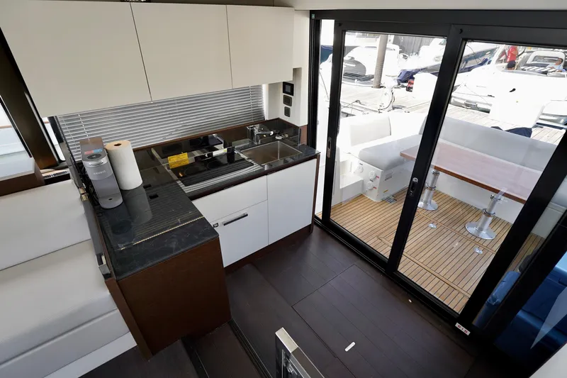  Yacht Photos Pics Modern kitchen interior on 2023 Prestige 460 yacht with sliding glass doors and outdoor seating.