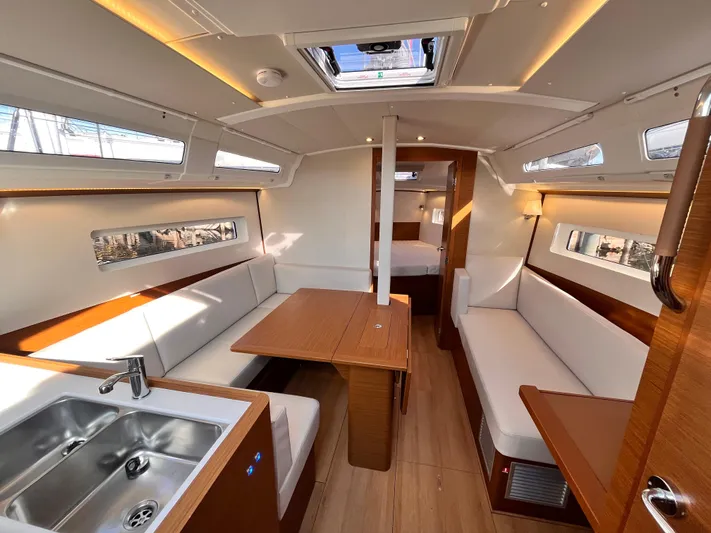  Yacht Photos Pics Interior of 2024 Jeanneau 380 sailboat, featuring modern seating, dining area, and kitchenette.