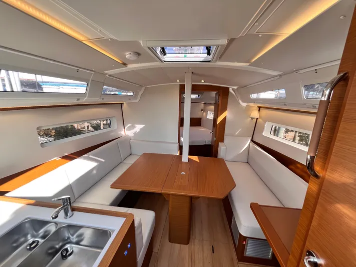  Yacht Photos Pics 2024 Jeanneau 380 yacht interior with modern seating, dining table, and kitchenette.