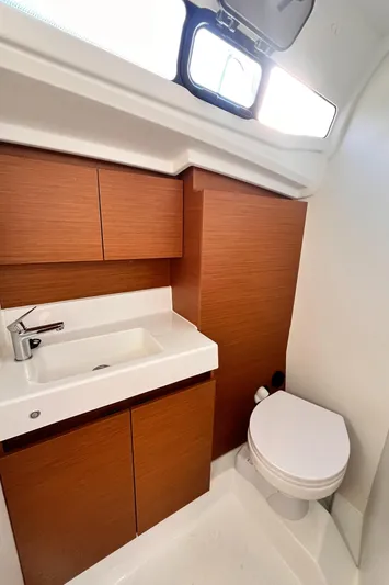  Yacht Photos Pics 2024 Jeanneau 380 yacht bathroom with modern sink, wooden cabinetry, and toilet.