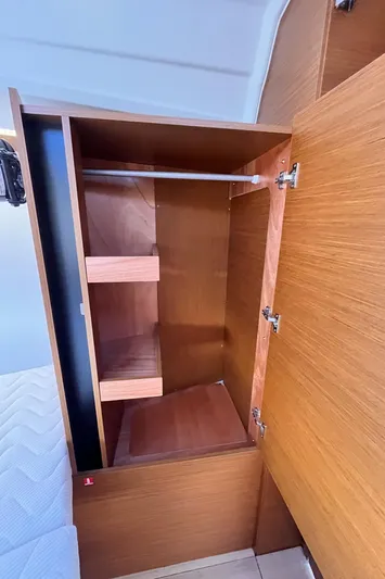  Yacht Photos Pics 2024 Jeanneau 380 interior wooden cabinet with shelves and hanging rod.