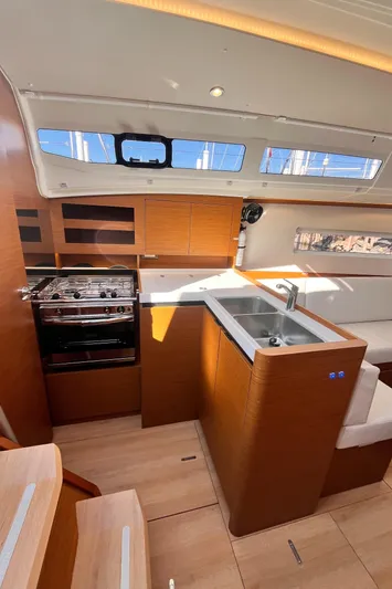  Yacht Photos Pics Modern kitchen interior of 2024 Jeanneau 380 yacht with wood finish and stainless steel appliances.