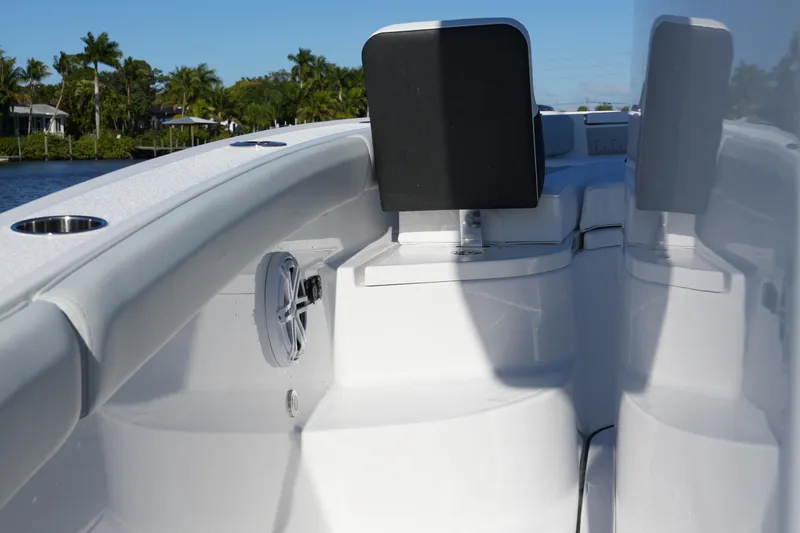Your Next Boat! Yacht Photos Pics 2026 Blackfin 242 HB boat interior with seating and speaker, docked by lush greenery.