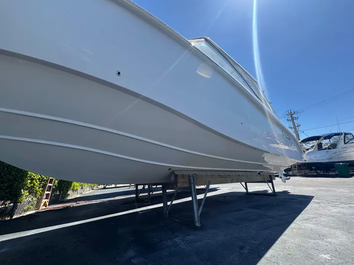  Yacht Photos Pics 2019 Everglades 340 Dual Console boat on stands, viewed from below, under clear blue sky.