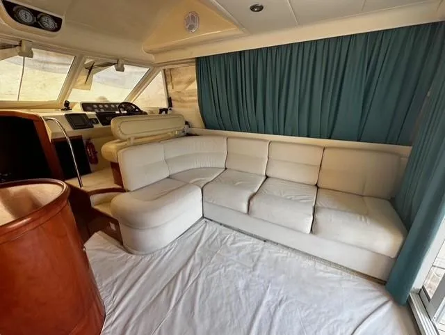  Yacht Photos Pics Interior of 1997 Fairline Phantom 37 yacht with cream sofa and blue curtains.