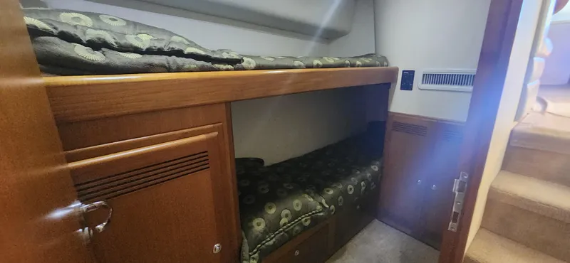 Laura K Yacht Photos Pics 2004 Cabo 48 Convertible yacht interior with wooden bunk beds and patterned bedding.