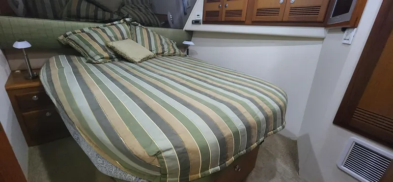 Laura K Yacht Photos Pics Cozy bedroom in 2004 Cabo 48 Convertible yacht with striped bedding and wooden cabinets.