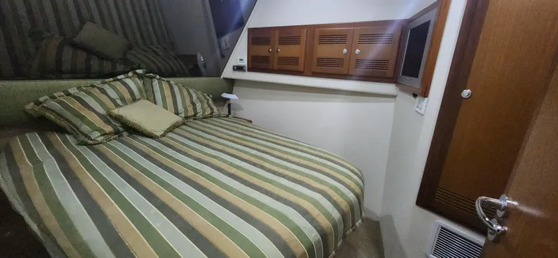 Laura K Yacht Photos Pics 2004 Cabo 48 Convertible cabin with striped bedding and wooden cabinetry.