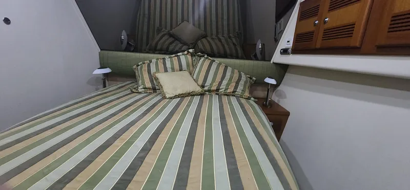 Laura K Yacht Photos Pics 2004 Cabo 48 Convertible cabin with striped bedding and wooden cabinets.