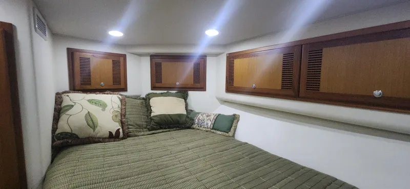 Laura K Yacht Photos Pics Cozy cabin interior of 2004 Cabo 48 Convertible with wood cabinets and patterned bedding.