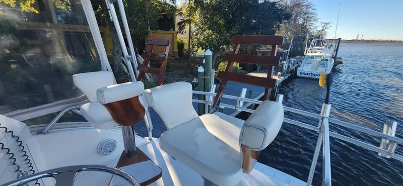 Laura K Yacht Photos Pics 2004 Cabo 48 Convertible yacht with seating, docked by a scenic waterfront.