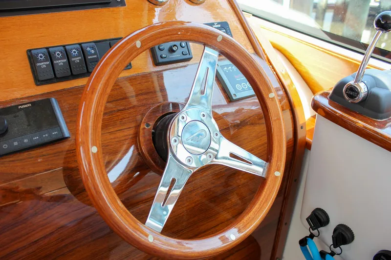 Sunny Daze Yacht Photos Pics Steering wheel of a 2008 Hinckley Talaria 38R Convertible yacht, featuring polished wood and metal accents.