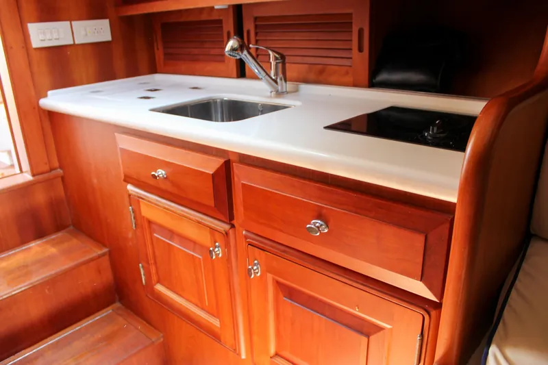 Sunny Daze Yacht Photos Pics 2008 Hinckley Talaria 38R Convertible yacht interior with wooden cabinetry and compact kitchen area.