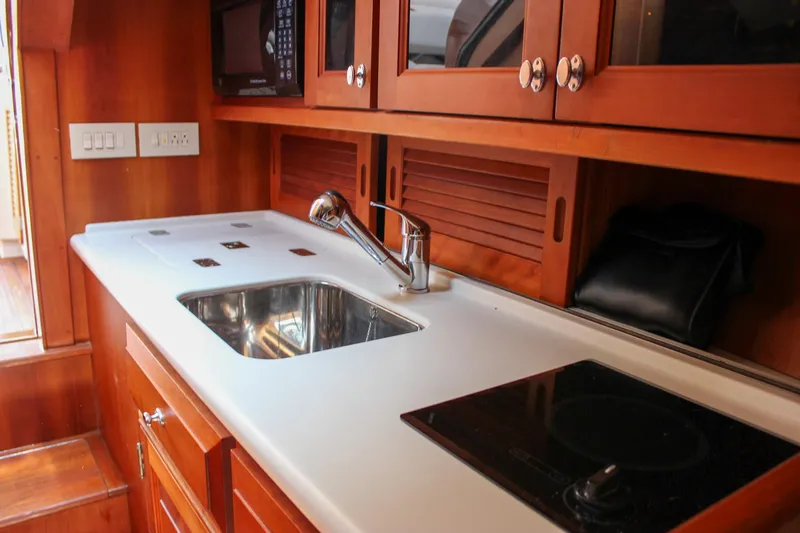 Sunny Daze Yacht Photos Pics 2008 Hinckley Talaria 38R Convertible yacht kitchen with sink, stove, and wooden cabinetry.