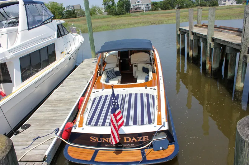 Sunny Daze Yacht Photos Pics 2008 Hinckley Talaria 38R Convertible docked, featuring striped seating and American flag.