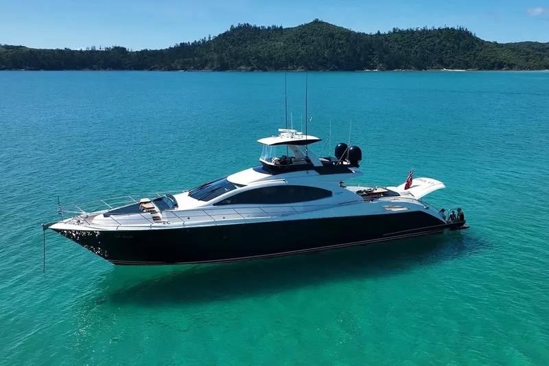 La Mar Yacht Photos Pics Luxury 2012 Lazzara LSX 78 yacht on turquoise waters, surrounded by lush green hills.