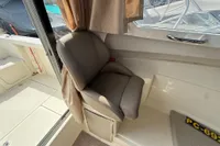 2019 Quicksilver 555 Pilothouse interior with cushioned seat and window view.
