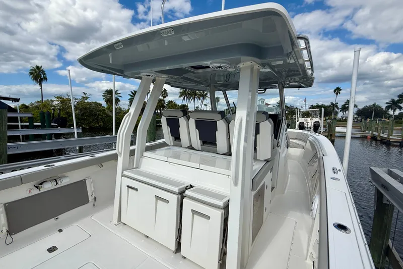  Yacht Photos Pics 2023 Pursuit S 358 Sport boat interior with seating and storage, docked under a cloudy sky.
