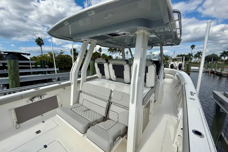  Yacht Photos Pics 2023 Pursuit S 358 Sport boat interior with seating, docked by palm trees.