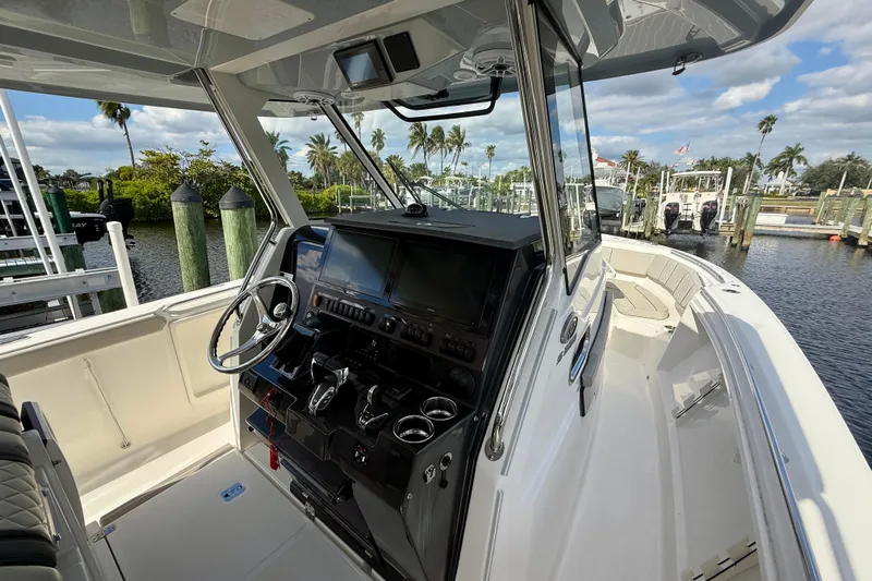 Yacht Photos Pics 2023 Pursuit S 358 Sport boat interior with modern dashboard and scenic marina view.